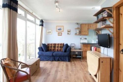 uma sala de estar com um sofá azul e uma televisão em Summercliffe Chalet No 75 em Swansea