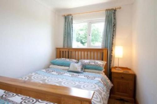 a bedroom with a wooden bed with a window at Summercliffe Chalet No 75 in Swansea