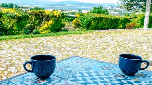 dos tazas azules sentadas en una mesa en un patio en The Quixote House, en Caminha