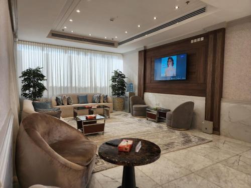 S Maskan Hotel في الدمام: غرفة معيشة مع أريكة وتلفزيون