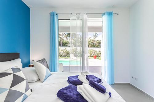 a bedroom with a bed with blue walls and a window at Villa BLUE in Saint-François