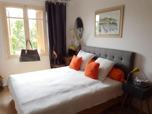 une chambre avec un grand lit blanc avec des oreillers orange dans l'établissement COMME UNE MAISON Clim et Ventilateurs aux pieds du port et des plages et 2km COLLIOURE, à Port-Vendres