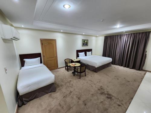a hotel room with two beds and a table at شركة اس مسكن الفندقية in Dammam