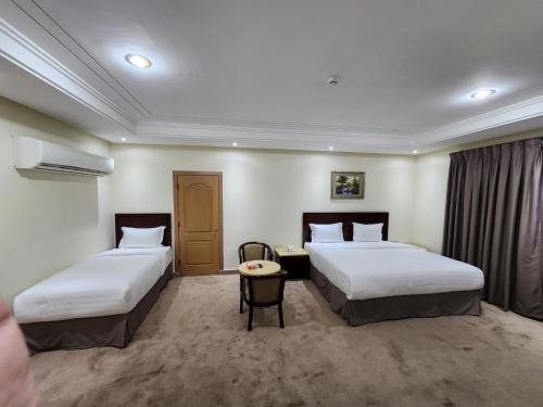 a hotel room with two beds and a table at شركة اس مسكن الفندقية in Dammam
