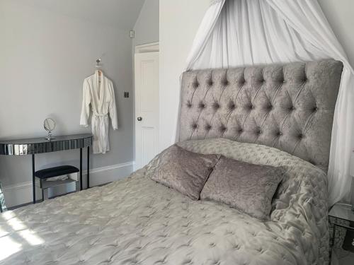 a bedroom with a bed with a tufted headboard at Pollokshields Burgh Hall Lodge Houses in Glasgow