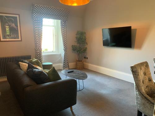a living room with a couch and a tv at Pollokshields Burgh Hall Lodge Houses in Glasgow