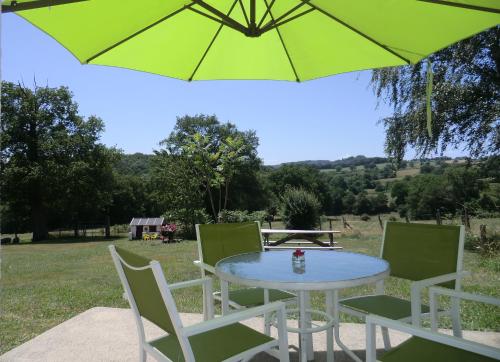 une table et des chaises avec un parasol vert dans l'établissement La Mez a Nine chambres d'hôtes, à Buxières-sous-Montaigut