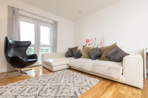 Newly refurbished apartment في Elmers End: غرفة معيشة مع أريكة بيضاء وكرسي أسود
