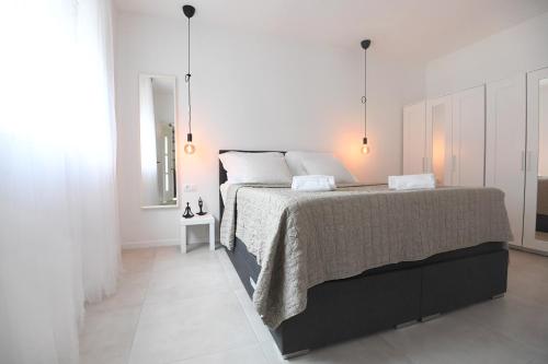 a bedroom with a large bed with white walls at Kala House in Zadar