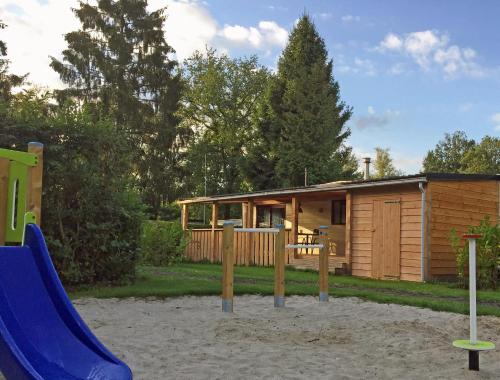 a log cabin with a slide and a playground at Chalet met Veranda en whirlpool gelegen in NP Drents Friese Wold, camping met zwembad 70 in Wateren