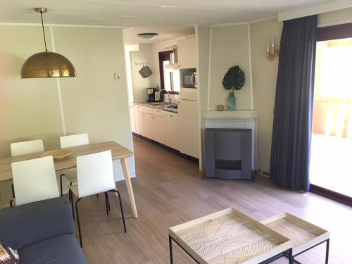 a living room with a table and a kitchen at Chalet met Veranda en whirlpool gelegen in NP Drents Friese Wold, camping met zwembad 70 in Wateren