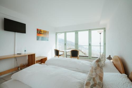 2 Betten in einem Zimmer mit Tisch und Stühlen in der Unterkunft Hotel Sonne in Amden