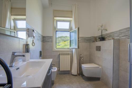 uma casa de banho com um lavatório, um WC e uma janela. em Etna Sicilian House em Linguaglossa