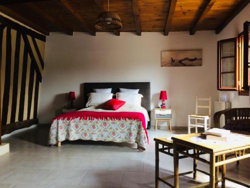 une chambre avec un grand lit avec une couverture rouge dans l'établissement La Tuillière, à Saint-Étienne-de-Puycorbier