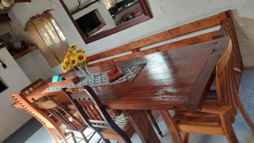 a wooden table with chairs and a vase of flowers on it at 11 Mountain Stream Hot Tub Self Catering in Gordonʼs Bay