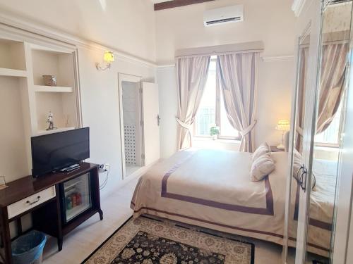 a white bedroom with a bed and a television at SOFIA BOUTIQUE HOTEL in Kérynia