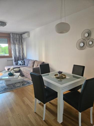 ein Wohnzimmer mit einem weißen Tisch und Stühlen in der Unterkunft Stylish New Belgrade apt parking 5e per day in Belgrad