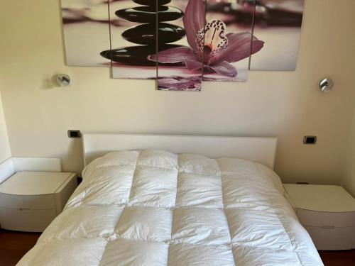 a white bed in a bedroom with two paintings on the wall at La Terrazza Sul Lago in Ossuccio