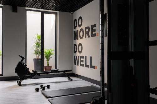 a gym with a treadmill and a wall with the words do more do well at THE ELEMENTS HOTEL in Tashkent