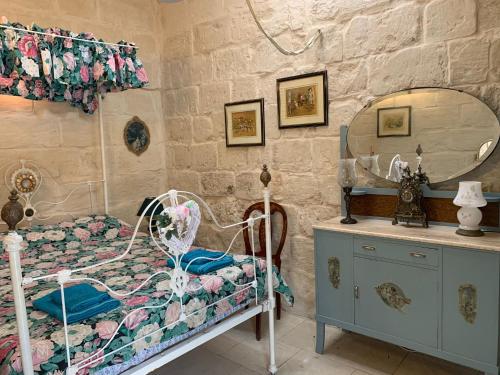 a bedroom with a bed and a mirror and a dresser at Traditional Maltese House in centre of Town in Mosta