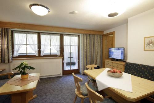 a living room with a table and chairs and a television at Pension Wendlhof in Obergurgl