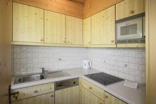 a kitchen with wooden cabinets and a sink and a microwave at Pension Wendlhof in Obergurgl