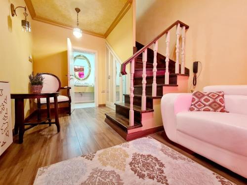 a living room with a pink couch and stairs at SOFIA BOUTIQUE HOTEL in Kérynia