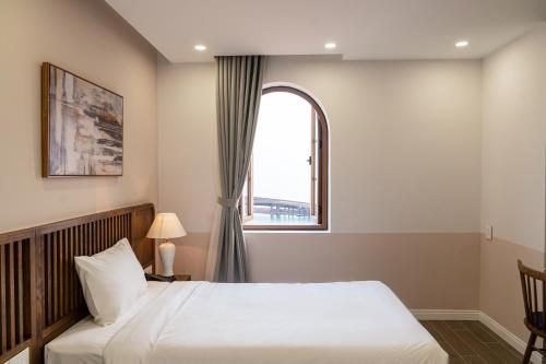 a bedroom with a large bed and a window at Palo Santo Hotel Phu Quoc in Phu Quoc