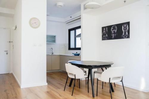 a kitchen and dining room with a black table and white chairs at View of Paradise in Bat Yam