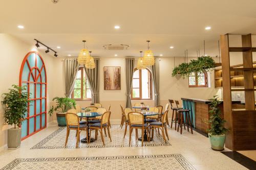 a dining room with tables and chairs and windows at Palo Santo Hotel Phu Quoc in Phu Quoc