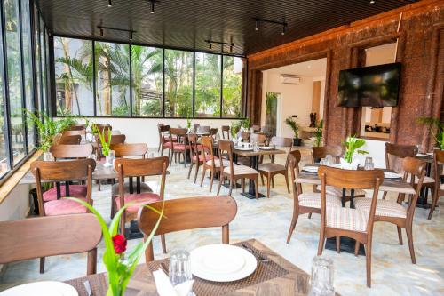 a restaurant with tables and chairs and windows at Hotel Meraden Opus , Anjuna Beach Goa in Anjuna