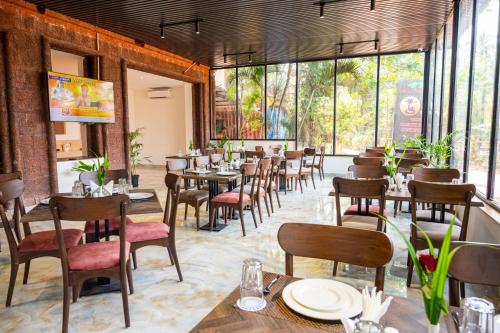 a restaurant with tables and chairs and large windows at Hotel Meraden Opus , Anjuna Beach Goa in Anjuna