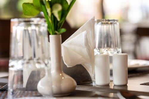a table with a white vase with a plant in it at Hotel Meraden Opus , Anjuna Beach Goa in Anjuna