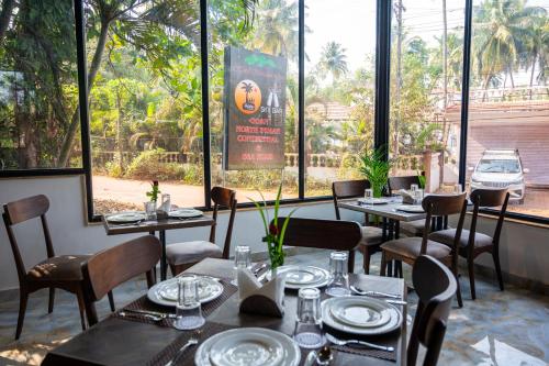 a restaurant with tables and chairs and large windows at Hotel Meraden Opus , Anjuna Beach Goa in Anjuna