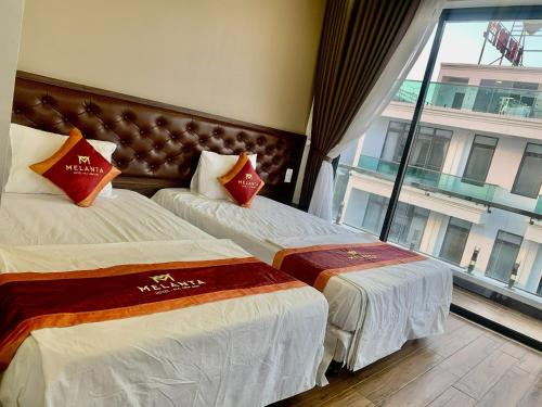 a hotel room with two beds and a large window at Melanta Hotel - FLC Sầm Sơn in Sầm Sơn