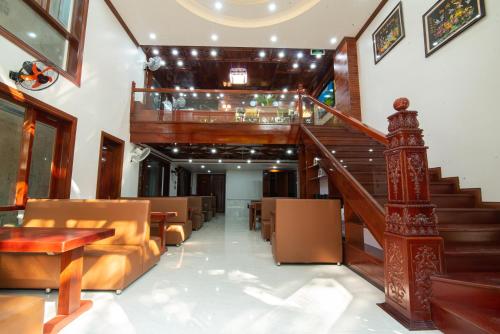 a lobby with a staircase and a couch and tables at Minh Quang Hotel in Dong Hoi