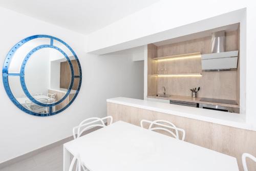 una cucina bianca con specchio e sedie bianche di Enkala Apartamentos a Ibiza Città