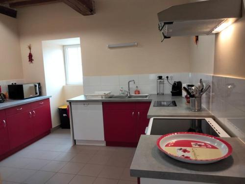 eine Küche mit roten Schränken und einem Teller auf der Theke in der Unterkunft Gîte de la tour in Guillon