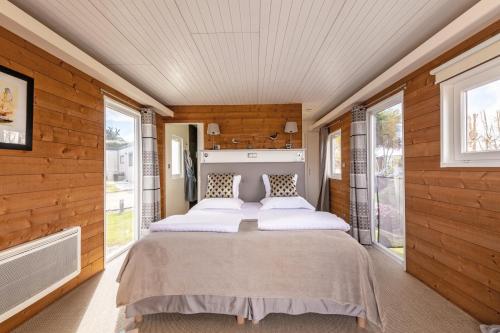 a bed in a room with wooden walls and windows at Le Theven in Sibiril
