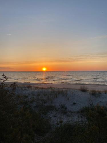 a sunset on a beach with the ocean at Apartament Riviera z tarasem - Playa Baltis in Międzyzdroje