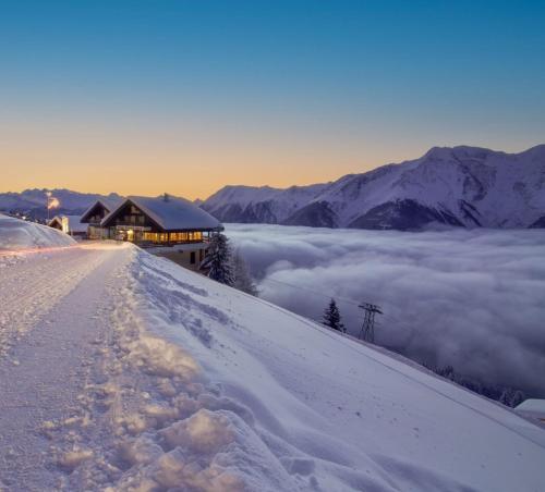 un edificio su una montagna innevata con uno strato di nuvole di Chalet Okkernoot a Breiten