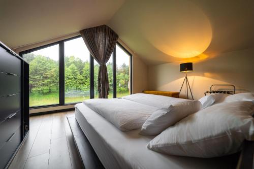 a bedroom with two beds and a large window at Bakony Deep Forest Vendégház in Bakonyszentlászló