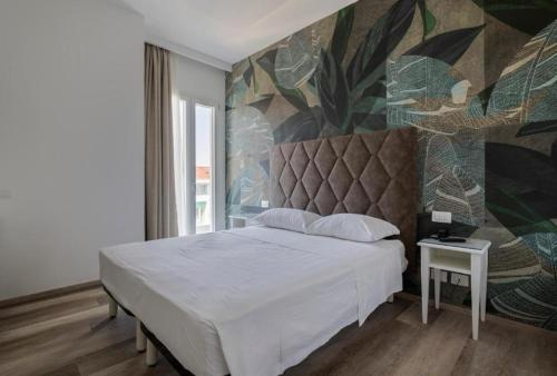 a bedroom with a white bed and a mural at Hotel President in Lido di Jesolo