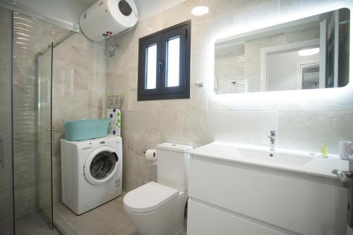 a bathroom with a toilet sink and a washing machine at Serenity Suites Corfu in Potamós