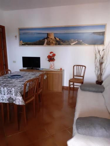 a dining room with a table and chairs and a desk at casa rosa nel residence mirice con piscina ,wifi,climatizzatore - vicino al mare in Aglientu