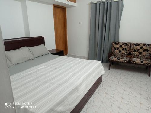 1 dormitorio con 1 cama grande y 1 silla en FAB HOUSE en Thekkadi