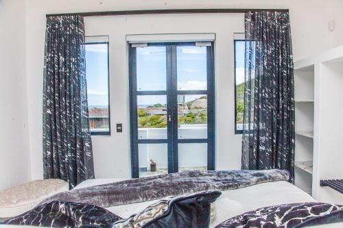 a bedroom with a window and a bed and a couch at Yzerfontein Villa Fantastica - No Loadshedding in Yzerfontein