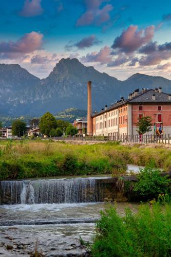 a factory next to a river with a waterfall at Casa Zefìra in Feltre