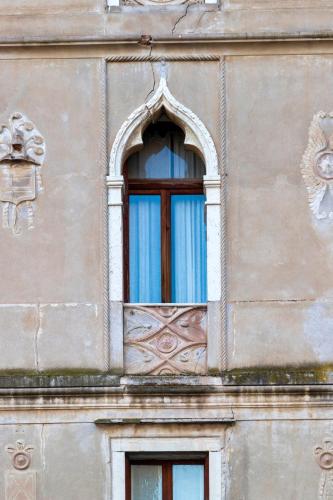 a window on the side of a building with blue curtains at Casa Zefìra in Feltre
