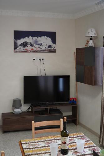 uma sala de estar com uma televisão de ecrã plano e uma mesa em Aragats Hostel & Guest House em Guiumri